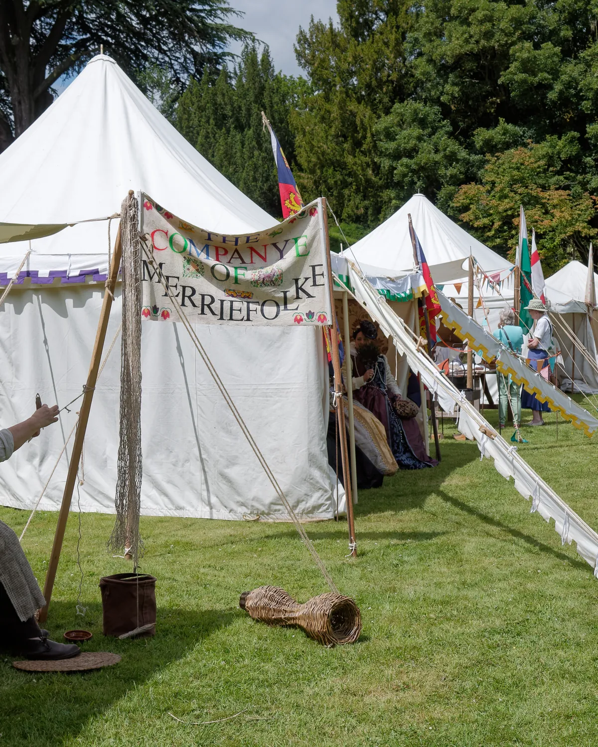 A white marquee on a lawn with guests gathered at an open-air event