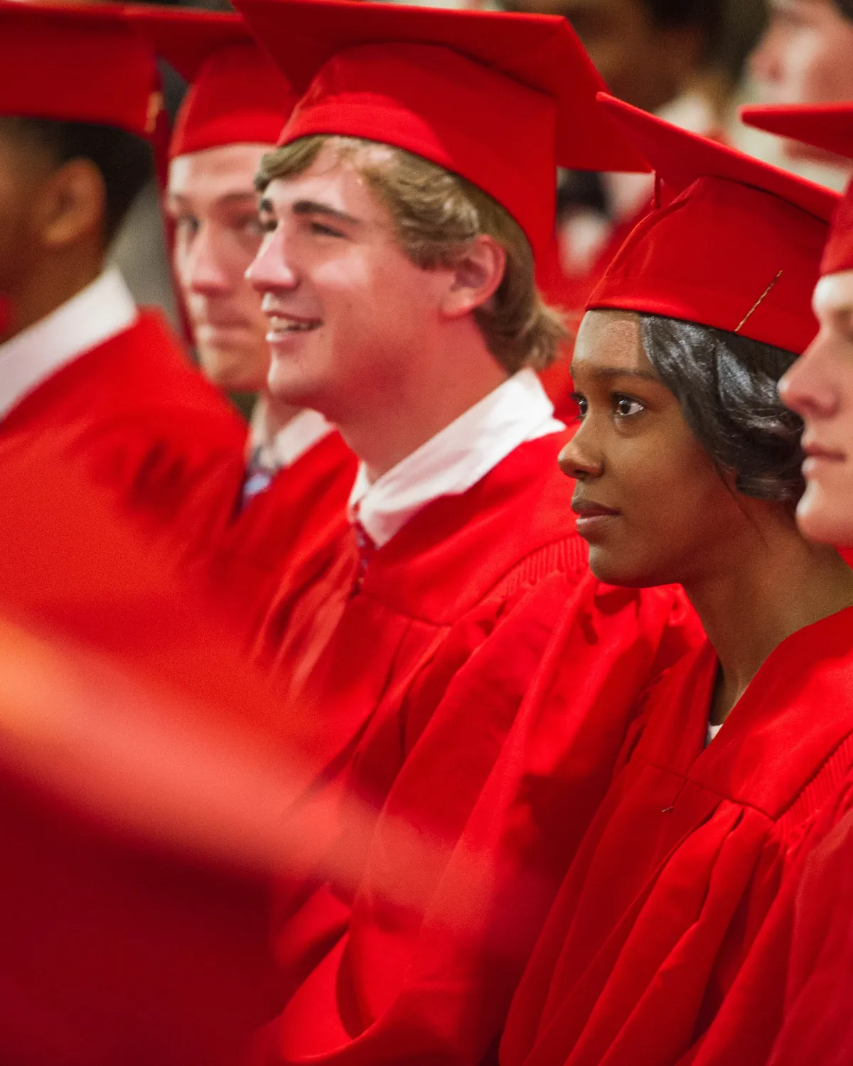 Graduates in red caps and gowns smiling during a commencement ceremony