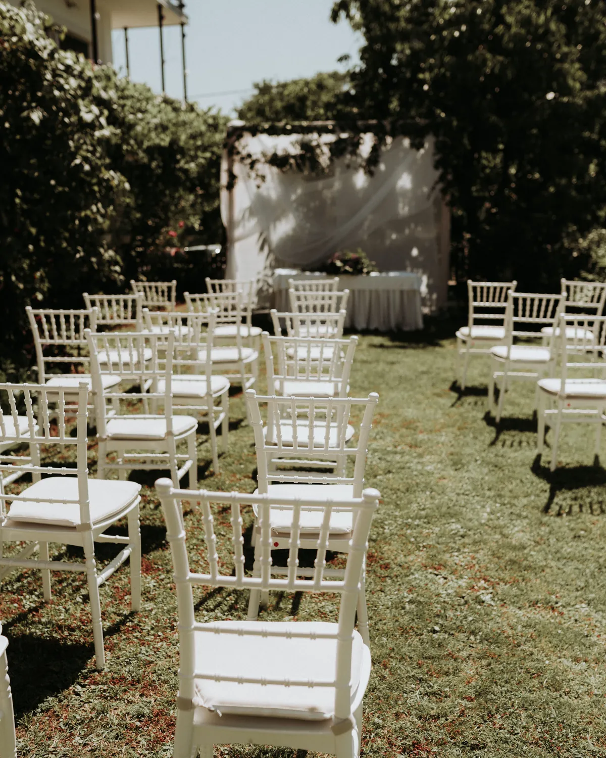 Rows of white chairs set out on a lawn for an outdoor wedding ceremony
